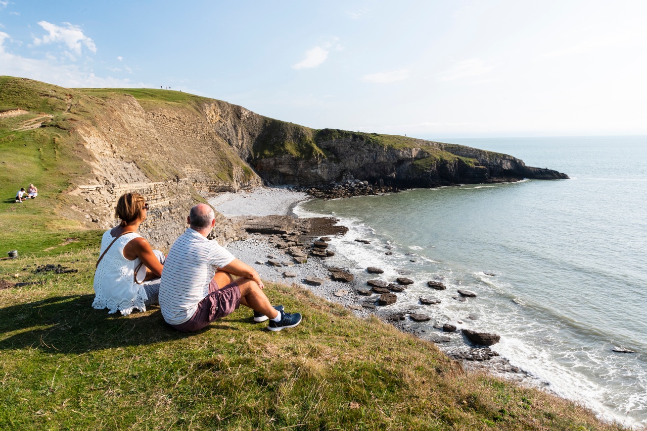 A beautiful afternoon view of two people overlooking Southerndown beach and ocean at high tide near to Wagon House Holiday Cottages. Wagon House Holiday Cottages are in the beautiful Vale of Glamorgan, Wales. The converted holiday cottages are situated in a quiet village only 10 minutes walk from the sea.