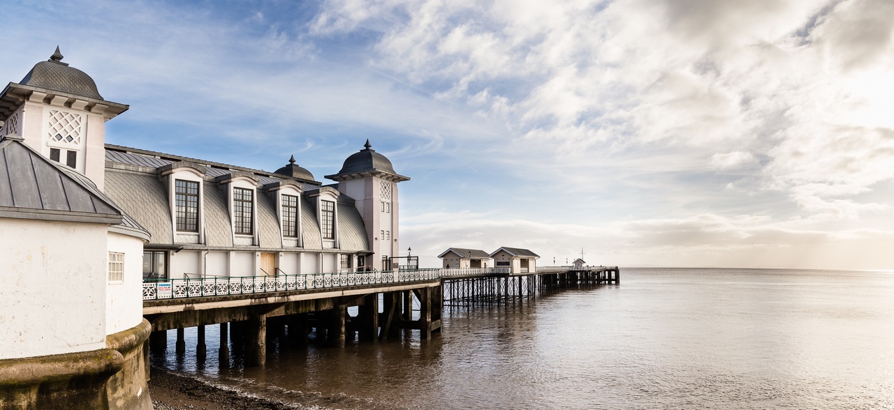 A beautiful view of Penarth Pier and the beach and ocean at high tide near to Wagon House Holiday Cottages as the sun goes down. Wagon House Holiday Cottages are in the beautiful Vale of Glamorgan, Wales. The converted holiday cottages are situated in a quiet village only 10 minutes walk from the sea.